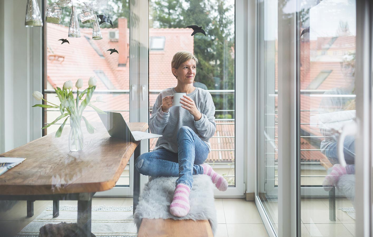 Frau sitzt am Tisch - man sieht sie durch die Fenster von außen